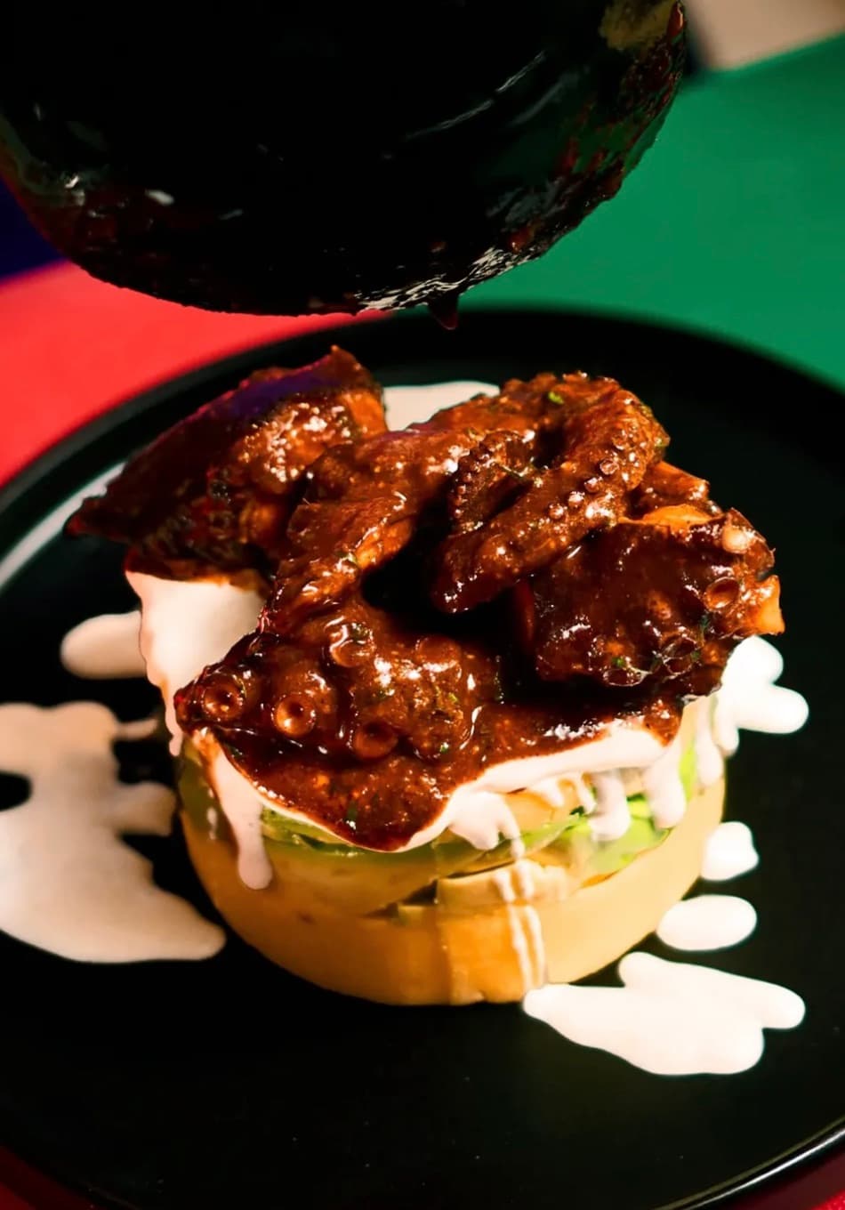 Salsa anticuchera cayendo sobre una causa de pulpo en Bitute